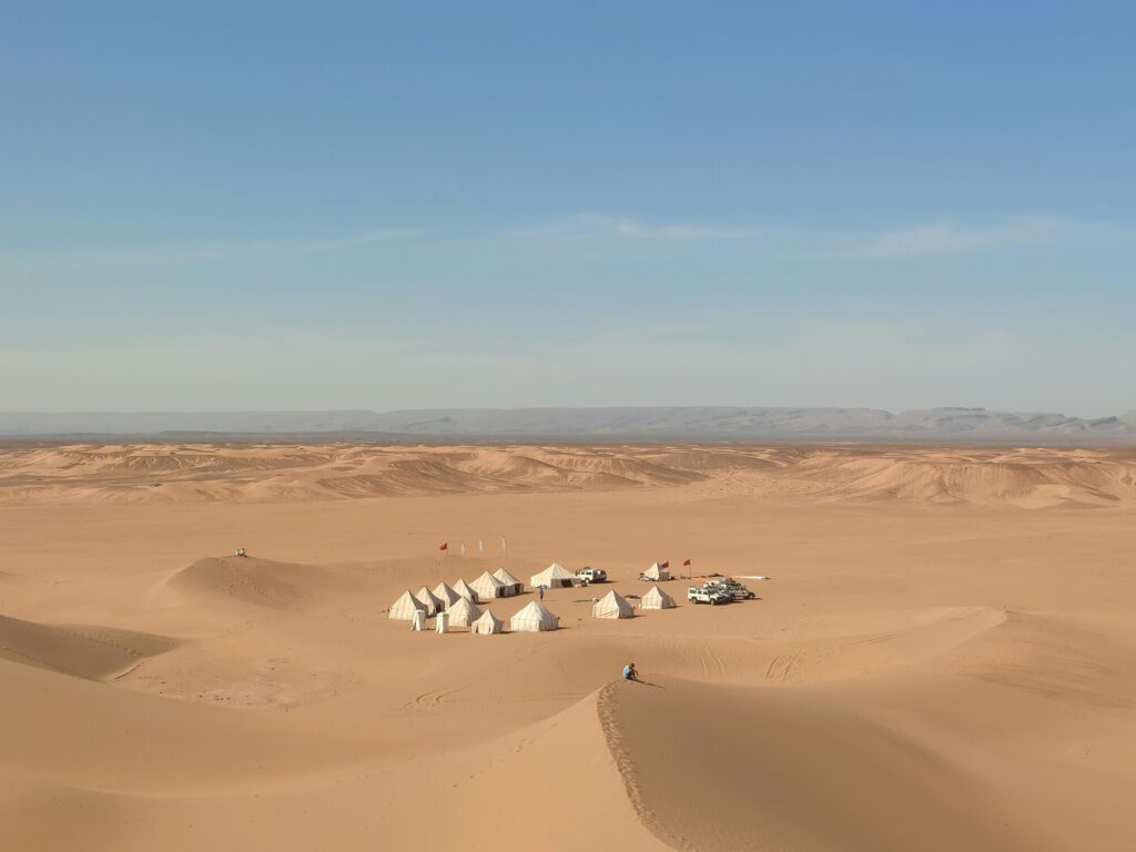 Explore the serene beauty of an isolated desert camp amidst the Sahara dunes in Morocco.
