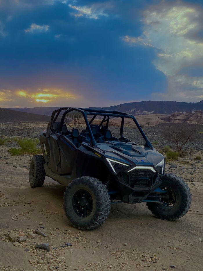 Balade Journée en buggy dans le desért d'Agafay Off-road buggy parked in a scenic desert at sunset, showcasing adventure and exploration.